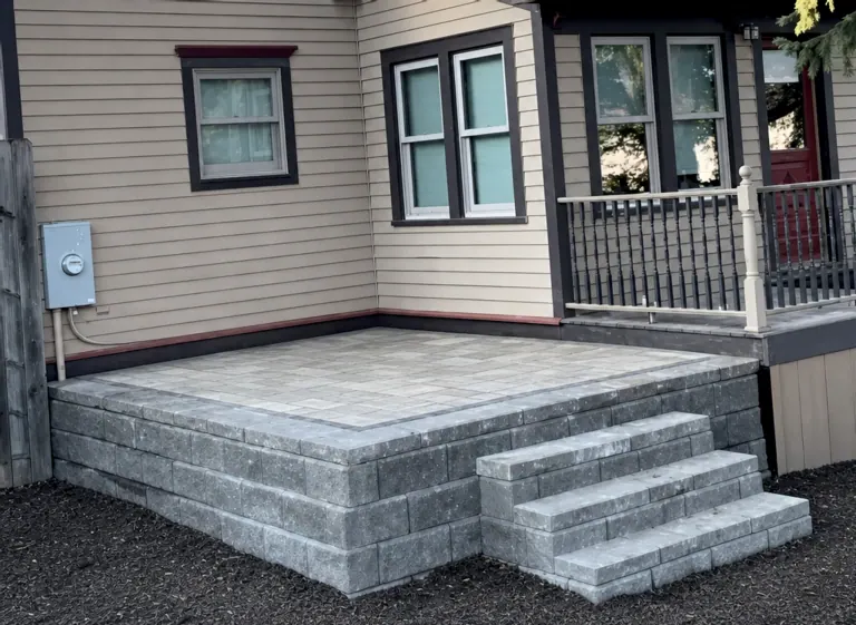 Completed raised paver patio with stone steps and retaining wall