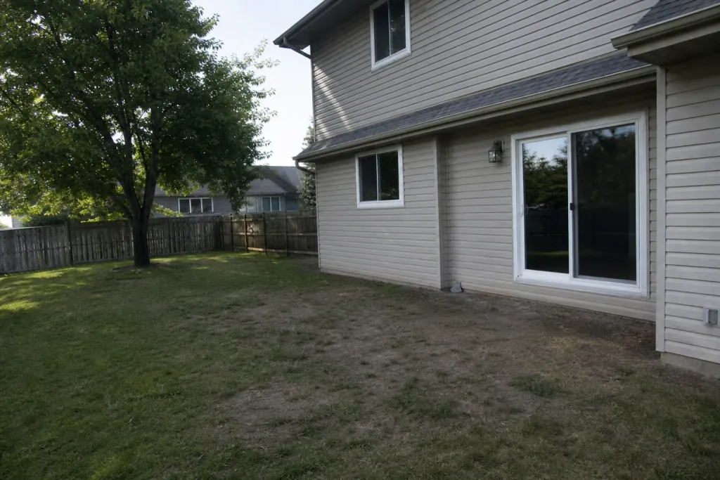 Backyard with worn grass before paver patio installation